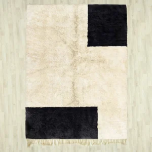 A handcrafted Beni Ourain rug with a minimalist design, featuring bold black geometric accents on a soft cream background, made from 100% wool