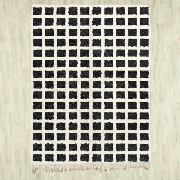 A black and white checkerd Beni Ourain rug featuring a bold grid pattern, handwoven with 100% natural wool, displayed on a wooden floor