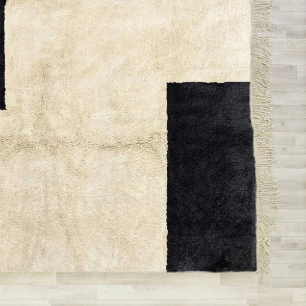 A handcrafted Beni Ourain rug with a minimalist design, featuring bold black geometric accents on a soft cream background, made from 100% wool